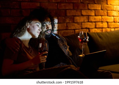 Diverse Married Couple Drinking Red Wine While Watching Films, Movies, Comedy. Beautiful Woman Love Spending Time With Boyfriend At Home