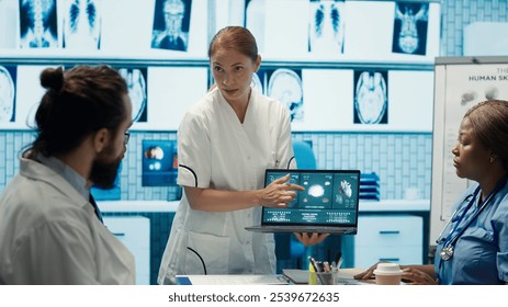 Diverse medical team examining test results and discussing innovative treatment plans at a modern clinic to enhance patient care quality. Doctors and nurses review x ray scans. Camera A. - Powered by Shutterstock