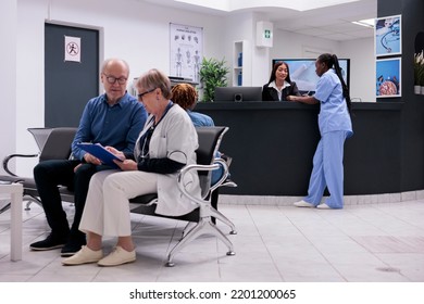 Diverse Medical Team Working At Reception Desk, Filling In Checkup Report Papers And Making Appointments. Nurse And Receptionist Doing Registration Work In Hospital Waiting Room.