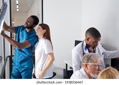 diverse medical workers radiologists looking at brain x-ray, discussing diagnosis