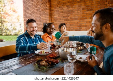 Diverse Mid Adult Friends Sharing And Enjoying Meal Together At Dining Table. Copy Space