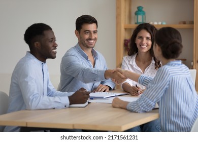 Diverse millennial ambitious business partners coming to agreement, handshake accomplish negotiations at group meeting, establishing partnership, make deal feeling satisfied. Succeed result concept