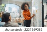 Diverse Modern Office: Black Businesswoman Leads Business Meeting with Managers, Talks, Explains Statistics, Uses a Whiteboard with Graphs, Big Data. Digital Entrepreneurs Work on eCommerce Project