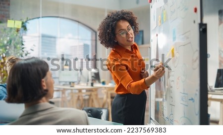 Diverse Modern Office: Black Businesswoman Leads Business Meeting with Managers, Talks, Explains Statistics, Uses a Whiteboard with Graphs, Big Data. Digital Entrepreneurs Work on eCommerce Project