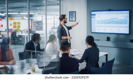 Diverse Modern Office: Motivated Businessman Leads Business Meeting with Managers, Talks, uses Presentation TV with Statistics, Chart Growth, Big Data. Digital Entrepreneurs Work on e-Commerce Project - Shutterstock ID 2101929379