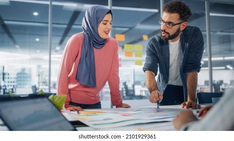 Diverse Modern Office: Muslim Businesswoman Wearing Hijab And Stylish Hispanic Entrepreneur Lead Business Meeting, Use Laptop, Talk, Brainstorm With Managers. Young Professionals On E-Commerce Project