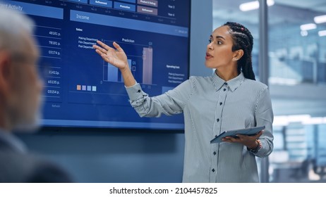 Diverse Modern Office: Successful Black Digital Entrepreneur Uses Tablet Computer And TV Screen With Big Data, Statistics, Talks About Company Growth. Investor, Top Managers, Executives Discuss Graphs