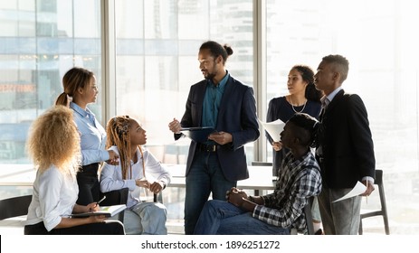 Diverse multiethnic businesspeople gather at casual meeting in office, brainstorm over business project together. Multiracial colleagues talk discuss company financial paperwork. Teamwork concept.