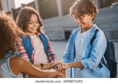 Diverse multiethnic elementary middle school kids children pupils classmates friends boys and girls are holding hands together at the yard. Unity teamwork playing together support concept - Powered by Shutterstock