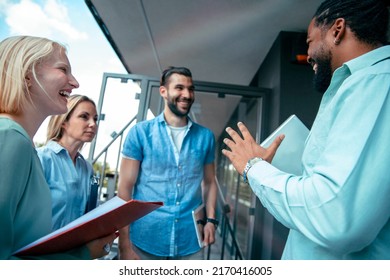 Diverse multiethnic young happy colleagues discussing work in a casual meeting at office terrace. Business people talking on casual brief in work break - Powered by Shutterstock