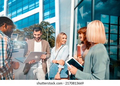 Diverse multiethnic young happy colleagues discussing work in a casual meeting in front of office building, talking about new ideas and plans - Powered by Shutterstock