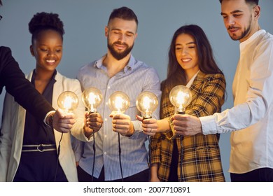 Diverse multinational group of smiling people holding illuminated lightbulb joining together brainstorming and sharing creative idea on startup project studio shot on grey background - Shutterstock ID 2007710891