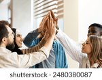 Diverse, multinational team of coworkers celebrating success with a high five in a bright office setting, embodying teamwork and unity. Teamwork concept