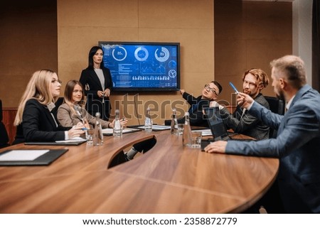 A diverse multinational team of professional business people meet in the conference room of a modern office. Creative team at the table discussing data analysis and planning a marketing campaign