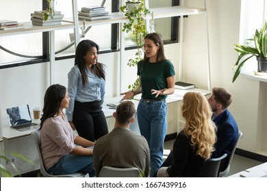 Diverse multiracial businesspeople gather at briefing brainstorm discuss company business ideas together, multiethnic colleagues talk consider financial startup project at office meeting