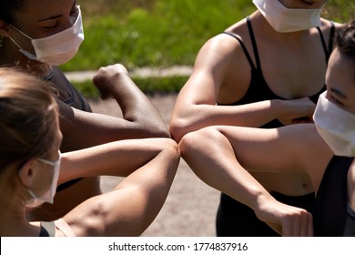 多種族適合女孩的朋友戴面罩給肘部凸起。運動型的非洲、印度和高加索年輕女性團體非接觸問候一起開始户外健身訓練。特寫