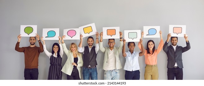 Diverse multiracial multiethnic people show various paper sheets and cards with pictures of different colorful mockup messenger and social media chat icons and message bubbles. Communication concept - Shutterstock ID 2143144193