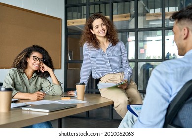 Diverse multiracial young happy cheerful coworkers businesswomen startup creative team students listening to mentor leader about project sitting at desk in contemporary office brainstorming ideas. - Shutterstock ID 2010062063
