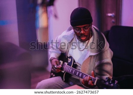 A diverse musician passionately plays an electric guitar in a cozy music studio, creating an artistic atmosphere. The ambient lighting highlights the creative process and musical expression.