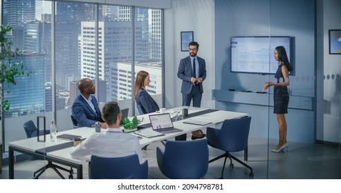 Diverse Office Conference Room Meeting: Male Executive And Asian Female Top Manager Present E-Commerce Fintech Startup Growth Statistics To A Group Of Investors. Wall TV With Infographics Data