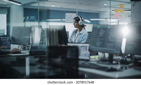 Diverse Office: Indian IT Programmer Working On Computer. Female Specialist Creating Innovative Software. Engineer Developing App, Program, Video Game. Wearing Headphones Listening Podcast, Music