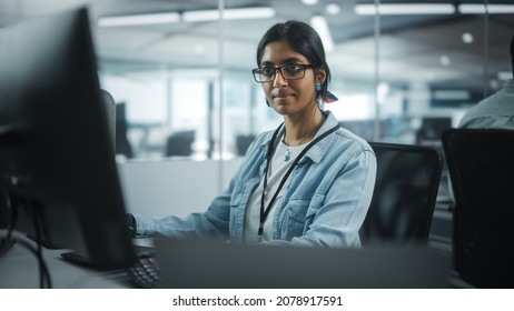 Diverse Office: Portrait Of Talented Indian Girl IT Programmer Working On Desktop Computer In Friendly Multi-Ethnic Environment. Female Software Engineer Wearing Glasses Develop Inspirational App