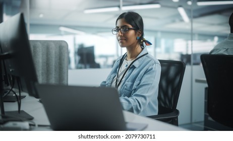 Diverse Office: Portrait Of Talented Indian Girl IT Programmer Working On Desktop Computer In Friendly Multi-Ethnic Environment. Female Software Engineer Wearing Glasses Develop Inspirational App