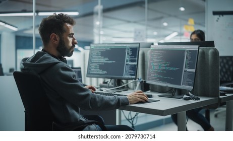 Diverse Office: IT Programmer Working on Desktop Computer. Male Specialist Creating Innovative Software Engineer Developing App, Program, Video Game. Terminal with Coding Language. Over Shoulder
