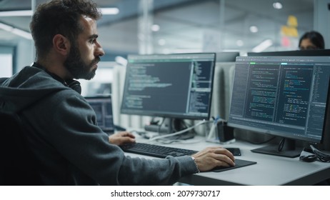 Diverse Office: IT Programmer Working On Desktop Computer. Male Specialist Creating Innovative Software Engineer Developing App, Program, Video Game. Terminal With Coding Language. Over Shoulder