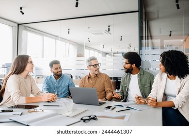 A diverse office team is engaged in a strategic meeting, with a senior colleague leading discussion, illustrating a productive and inclusive workplace. Colleagues engage in a lively exchange of ideas - Powered by Shutterstock