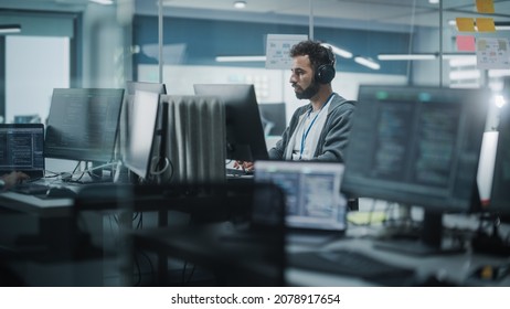 Diverse Office: White IT Programmer Working On Computer. Male Specialist Creating Innovative Software. Engineer Developing App, Program, Video Game. Wearing Headphones Listening Podcast, Music