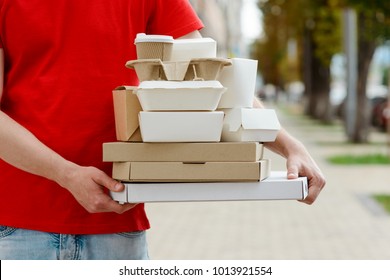 Diverse Of Paper Containers For Takeaway Food. Delivery Man Is Carrying Pizza, Chinese Noodles, Burgers And Coffee.