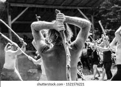 Diverse people enjoy spiritual gathering A black and white view of a mixed group of people from all backgrounds practicing tai chi with sticks in a forest clearing, exercises for mindfulness & health - Powered by Shutterstock