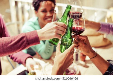 Diverse People Ethnicity Friends Hanging Out - Multiracial Dinner Contest With Food and Alcohol - Chill and Relax Concept - Pink Vintage Warm Filter - Focus On Bottom Bottle Hand
