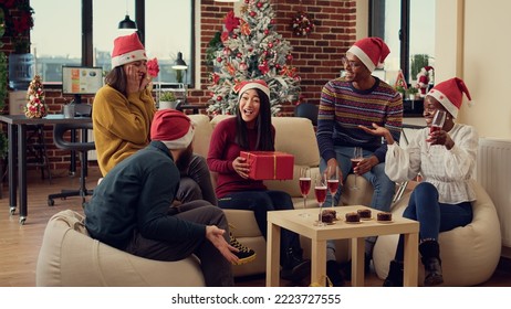 Diverse people exchanging presents at christmas party in office, celebrating holiday season together with xmas ornaments and lights. Making surprise gifts as seasonal winter tradition. - Powered by Shutterstock