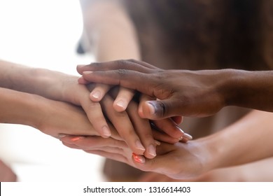 Diverse people group stacked joined hands in pile close up view, multiethnic team friends students together as racial unity concept, partnership coaching training, teambuilding, support in teamwork
