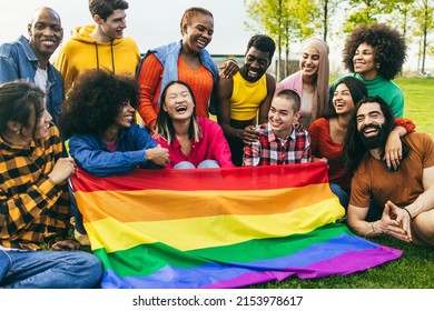 Diverse people having fun holding LGBT rainbow flag outdoor - Focus on center african woman face - Shutterstock ID 2153978617