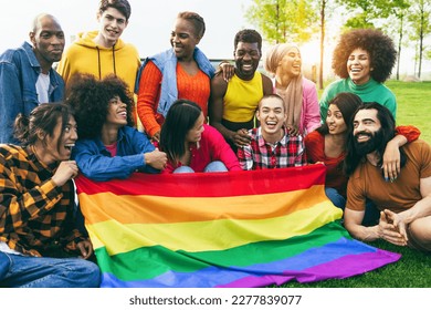 Diverse people having fun holding LGBT rainbow flag outdoor - Focus on african man face - Powered by Shutterstock