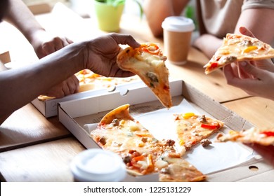 Diverse People Having Lunch Eating Fast Junk Food. Close Up Hands Diverse Multi-ethnic Students Holding Pieces Of Pizza Sitting At Table In Cafe. Unhealthy Eating And Meeting Of Best Friends Concept