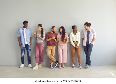 Diverse People Leaning On Studio Background And Talking. Full Body Length Indoor Group Shot Of Happy Young Men And Women Making Friends, Sharing And Listening To Opinions And Finding Common Grounds