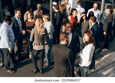 Diverse people mingle in business social event outdoors. Diverse group of people socializing outdoors. Men and women in conversation. Casual business gathering, lively interaction, diverse crowd. - Powered by Shutterstock