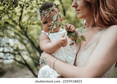 Diverse people portrait of mother with swarthy infant spending time in open air. Multi ethnic family having fun togetherness enjoying motherhood positive emotion motherly care summer vacation in park - Shutterstock ID 2259518823