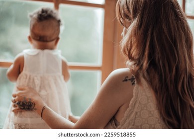 Diverse people portrait of mother with swarthy infant spending time at use light window. Multi ethnic family having fun togetherness enjoying motherhood positive emotion motherly care at home - Shutterstock ID 2259518855