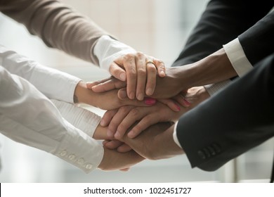 Diverse people putting stacked hands together promising help and support starting common business, black and white multiracial group unite at motivating training, team building concept, close up view
