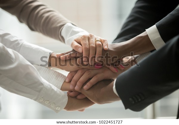Diverse people putting stacked hands together\
promising help and support starting common business, black and\
white multiracial group unite at motivating training, team building\
concept, close up view
