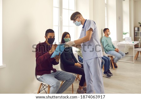 Diverse people signing papers while waiting in line to get influenza or coronavirus shots at the hospital or medical center. African-American man putting signature on Informed Consent for Vaccination