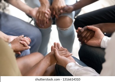 Diverse people sitting in circle holding hands at group therapy session, religious christian team pray together for recovery give psychological support, counseling training trust concept, close up