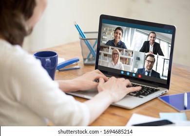 Diverse People Take Part In Group Video Call Pc Screen Cam App View Over Woman Shoulder, Seated At Desk. Solve Business Issues Distantly During Coronavirus Pandemic Outbreak, Videoconferencing Concept