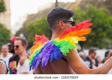 Diverse Person Walking At Pride Parade With Rainbow Flag Feathers As Symbol Of Pride Month. Queer Community March In The Street With Crowds. LGBTQIA March: VALENCIA, SPAIN - JUNE 25 2022