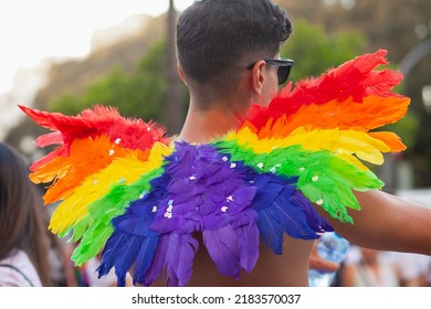 Diverse Person Walking At Pride Parade With Rainbow Flag Feathers As Symbol Of Pride Month. Queer Community March In The Street With Crowds. LGBTQIA March: VALENCIA, SPAIN - JUNE 25 2022